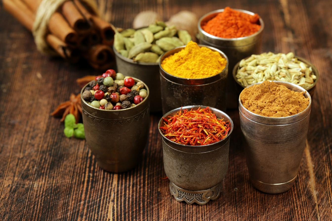 Copper cups filled with turmeric, paprika, cardamom, and peppercorns
