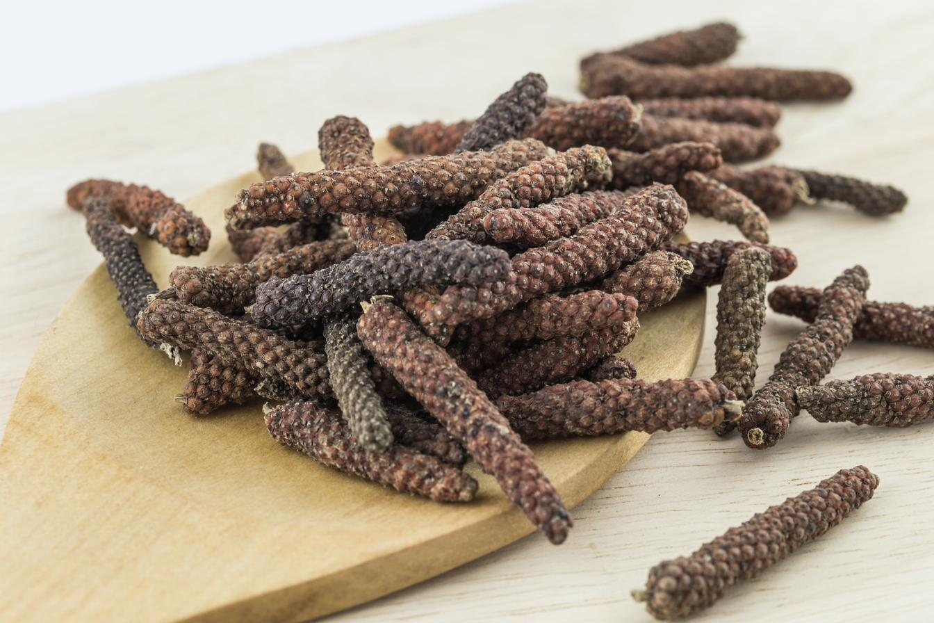 Long pepper catkins scattered across a pale wooden board